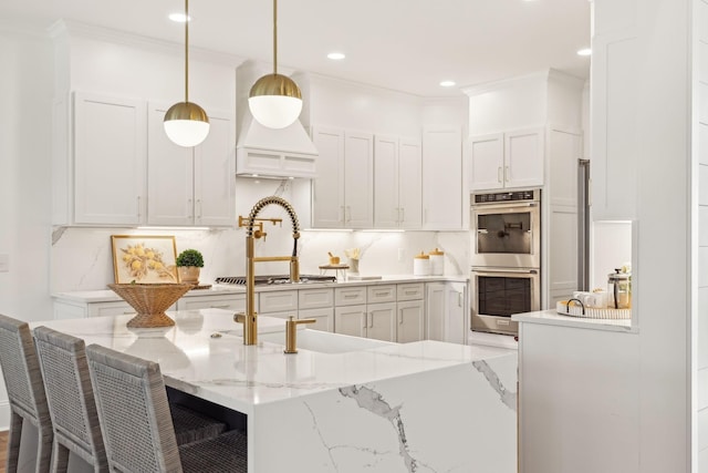 kitchen with light stone counters, ornamental molding, decorative light fixtures, a kitchen bar, and appliances with stainless steel finishes