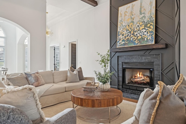 living room with a large fireplace, a towering ceiling, arched walkways, and crown molding
