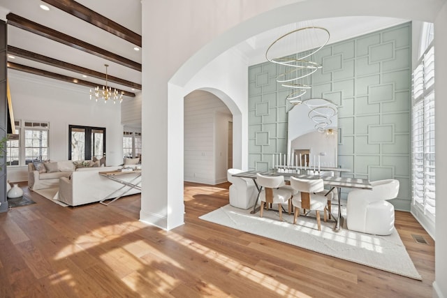 dining area featuring arched walkways, a towering ceiling, a notable chandelier, beam ceiling, and visible vents