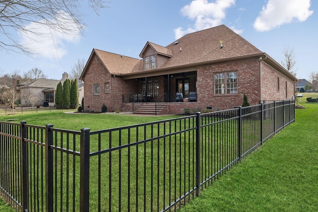 back of property with a fenced backyard, brick siding, a shingled roof, a yard, and crawl space