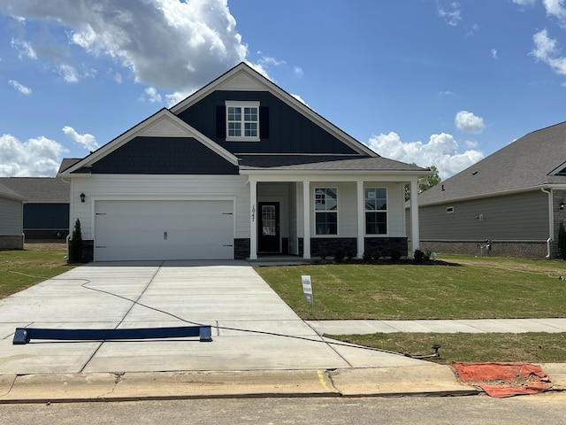 view of front facade with concrete driveway, stone siding, board and batten siding, an attached garage, and a front yard