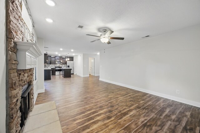 1200 Eagles Bluff Dr, Clarksville, TN 37040 - unfurnished living room featuring a ceiling fan, a stone fireplace, wood finished floors, baseboards, and recessed lighting