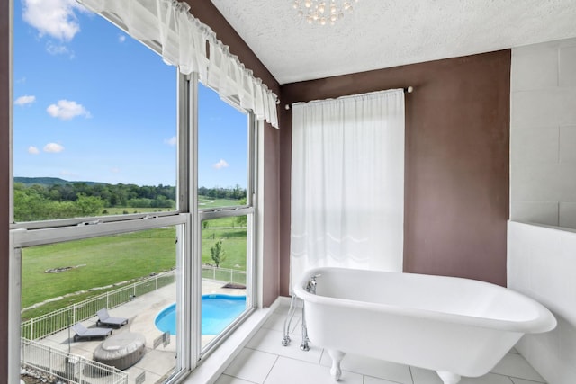 bathroom with a chandelier, tile patterned flooring, a textured ceiling, and a freestanding bath