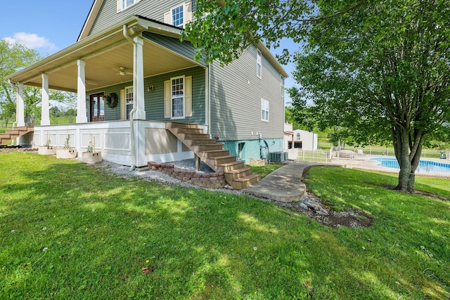 view of front facade with central air condition unit, a front lawn, covered porch, a fenced in pool, and stairs