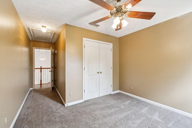 unfurnished bedroom featuring attic access, a closet, visible vents, and carpet