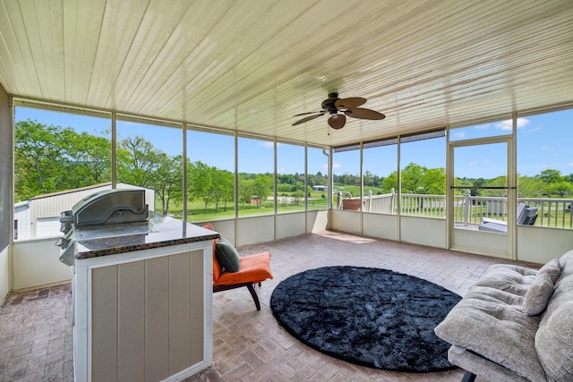sunroom featuring a ceiling fan and exterior kitchen
