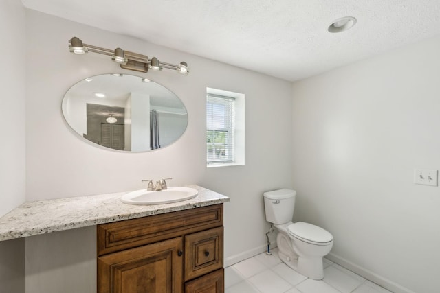 bathroom featuring a textured ceiling, vanity, baseboards, toilet, and tile patterned flooring