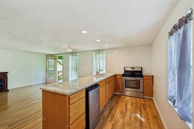 kitchen with gas range, a healthy amount of sunlight, a sink, and light wood-style flooring