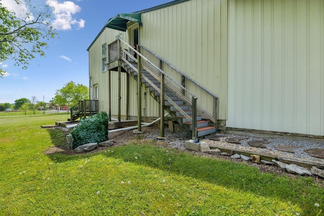 view of side of home with stairway and a yard