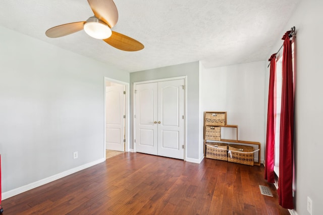 unfurnished bedroom featuring baseboards, wood finished floors, visible vents, and a closet