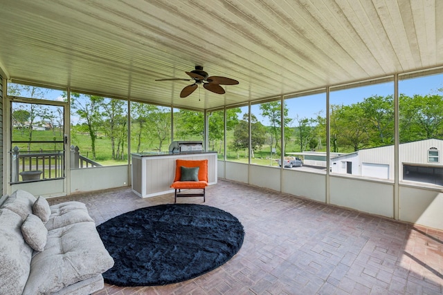 sunroom featuring a healthy amount of sunlight, ceiling fan, and area for grilling