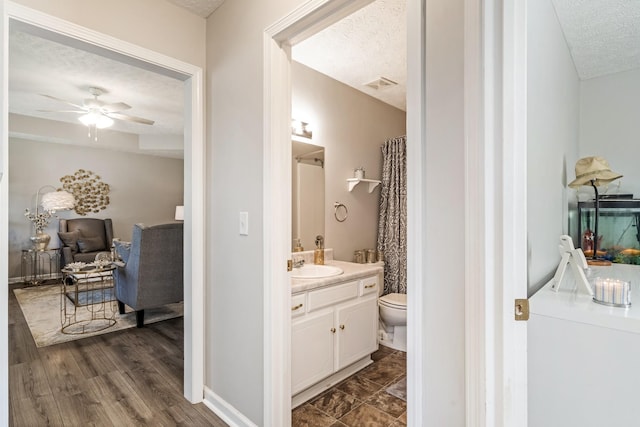 bathroom with ceiling fan, toilet, a textured ceiling, and visible vents