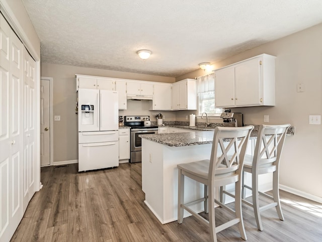 kitchen with white refrigerator with ice dispenser, stainless steel electric stove, a peninsula, under cabinet range hood, and dark wood-style floors