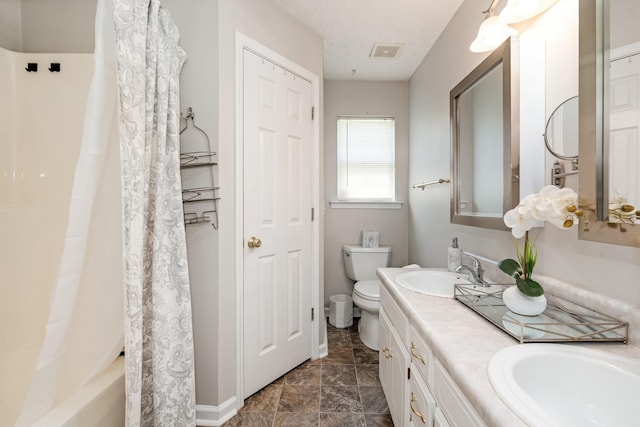 bathroom featuring toilet, visible vents, a sink, and double vanity