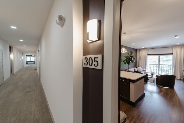 hallway with dark carpet, dark wood-type flooring, and recessed lighting
