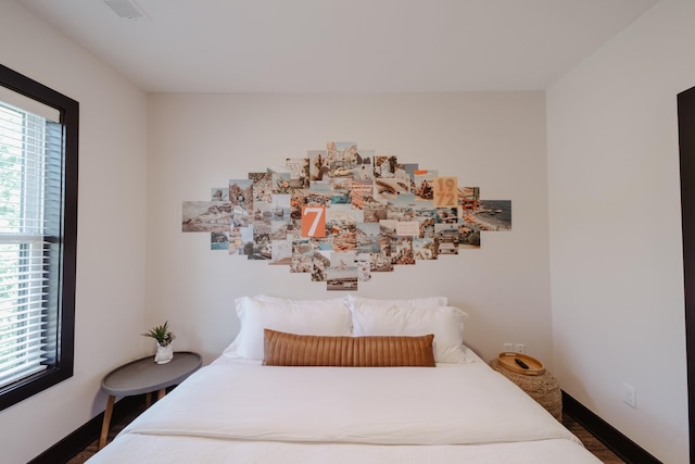 bedroom with wood finished floors, visible vents, and baseboards