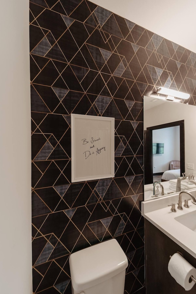 ensuite bathroom with tile walls, toilet, vanity, and connected bathroom