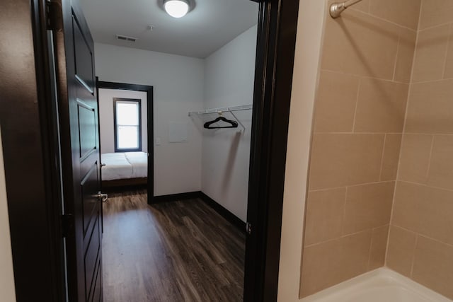 bathroom with shower / bath combination, baseboards, wood finished floors, and visible vents