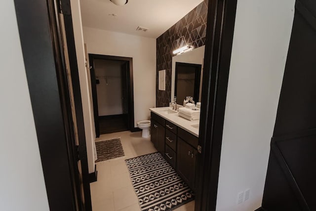 full bath with a spacious closet, double vanity, toilet, a sink, and tile walls