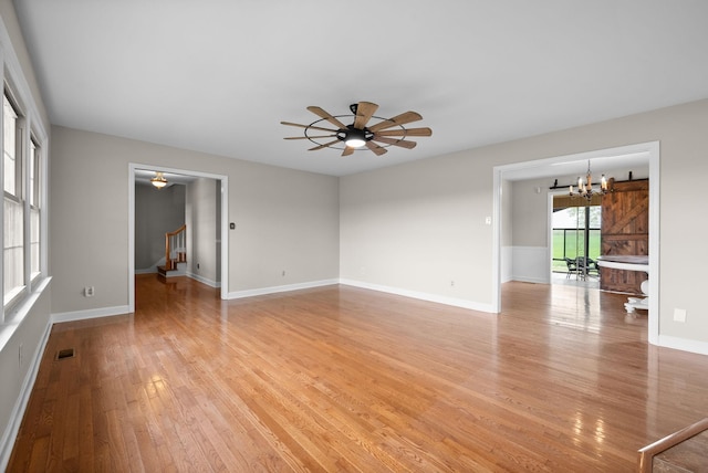 13391 Fruit Hill Red Bridge Rd, Crofton, KY 42217 - unfurnished living room with visible vents, baseboards, light wood-style flooring, stairs, and ceiling fan with notable chandelier