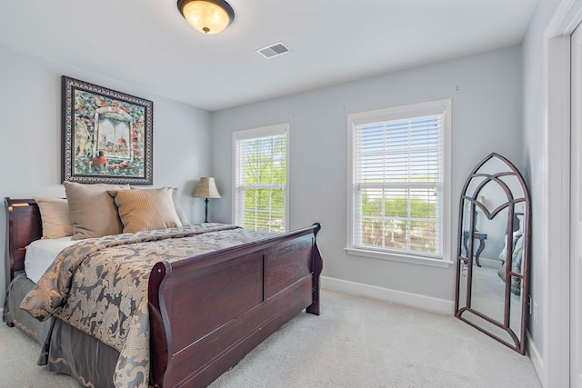 bedroom with baseboards, visible vents, and light carpet