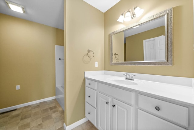 bathroom featuring visible vents, baseboards, vanity, and a washtub
