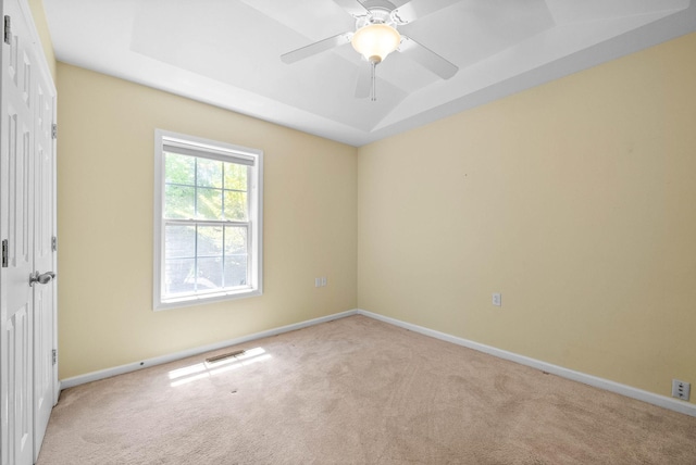 unfurnished room featuring light colored carpet, baseboards, and a raised ceiling