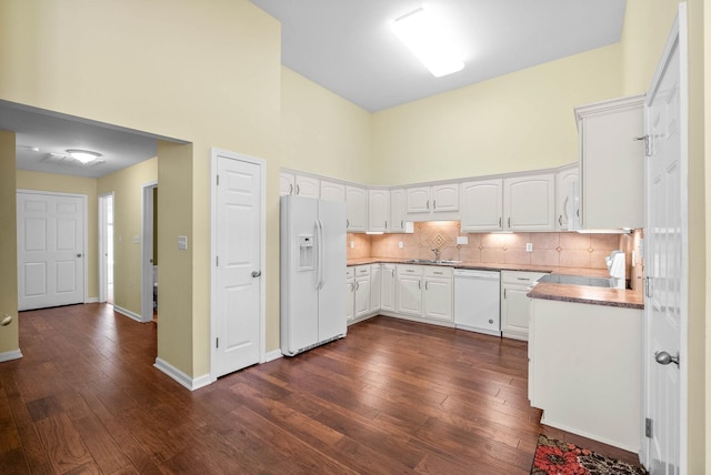 kitchen featuring tasteful backsplash, white appliances, a towering ceiling, white cabinetry, and dark wood-type flooring