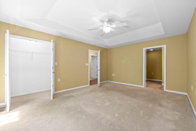 unfurnished bedroom featuring baseboards, light colored carpet, and a raised ceiling
