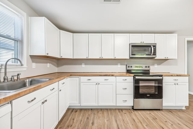 111 3rd Ave, Mount Pleasant, TN 38474 - kitchen with a sink, wood counters, light wood-style floors, stainless steel appliances, and white cabinetry