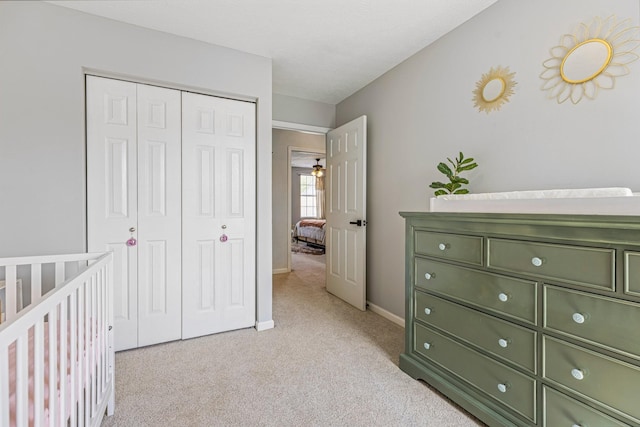 bedroom with baseboards, light carpet, and a closet