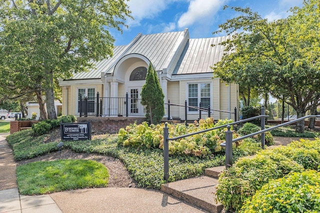 view of front of property with a standing seam roof, fence, and metal roof