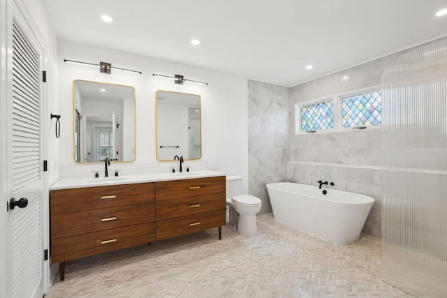 full bathroom with a soaking tub, a closet, double vanity, and a sink