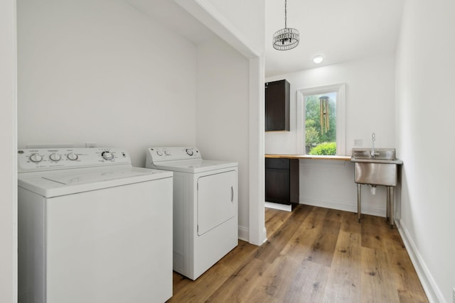 laundry room featuring light wood finished floors, a chandelier, washer and clothes dryer, laundry area, and baseboards