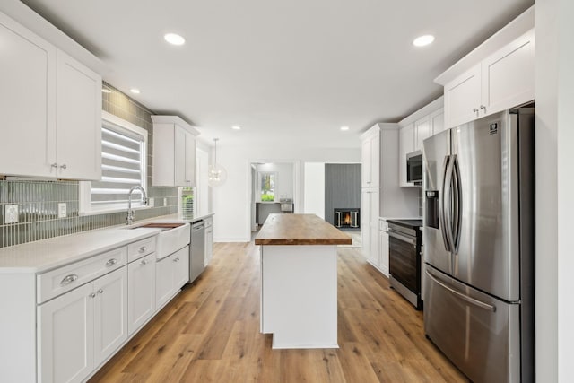 kitchen with recessed lighting, stainless steel appliances, tasteful backsplash, a kitchen island, and white cabinets