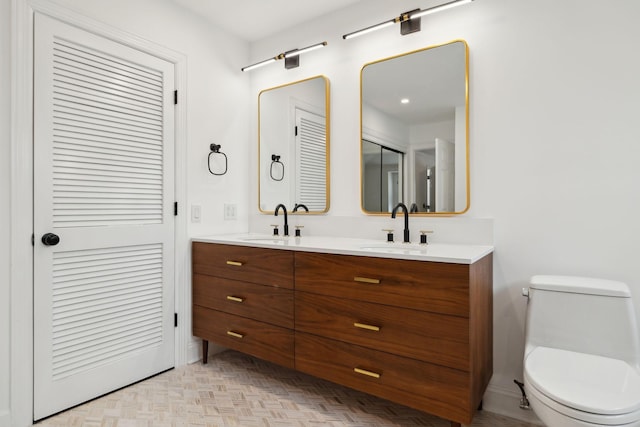 bathroom with toilet, double vanity, and a sink