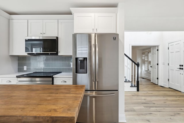 kitchen featuring stainless steel appliances, light wood-style floors, wooden counters, backsplash, and white cabinetry