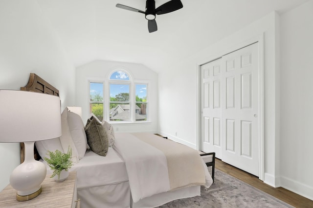 bedroom with wood finished floors, a closet, vaulted ceiling, baseboards, and a ceiling fan