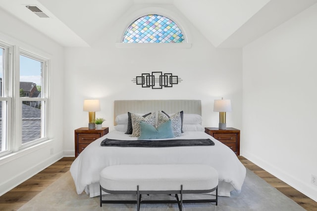bedroom featuring baseboards, visible vents, wood finished floors, and lofted ceiling