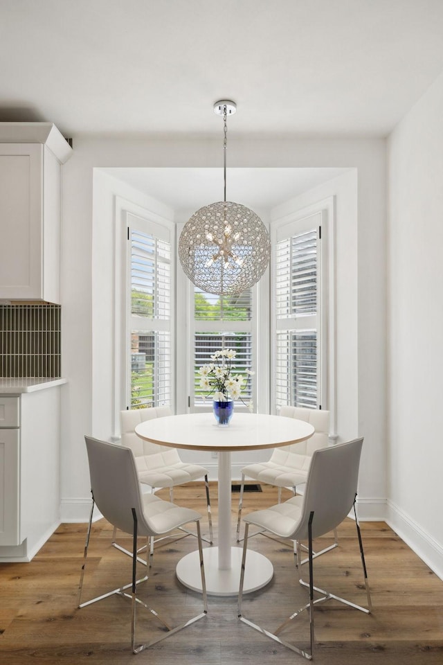 dining space with a chandelier, baseboards, and wood finished floors