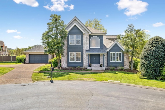traditional-style house featuring a front lawn, a shingled roof, driveway, brick siding, and fence