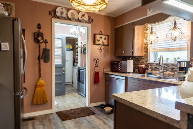 60 Sam Johnson Ln, Scotts Hill, TN 38374 - kitchen with crown molding, a sink, a chandelier, light wood-style floors, and appliances with stainless steel finishes