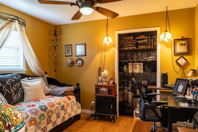 60 Sam Johnson Ln, Scotts Hill, TN 38374 - bedroom featuring wood finished floors, a wood stove, and ceiling fan