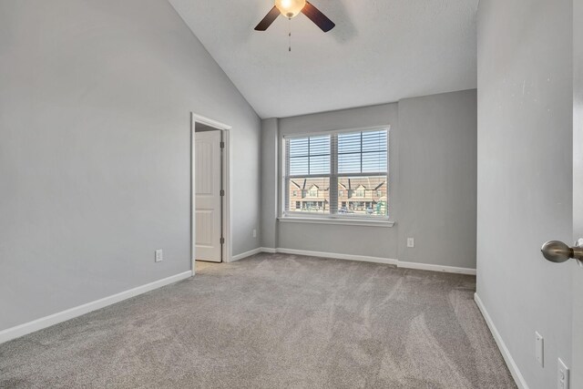 carpeted spare room with ceiling fan, lofted ceiling, and baseboards
