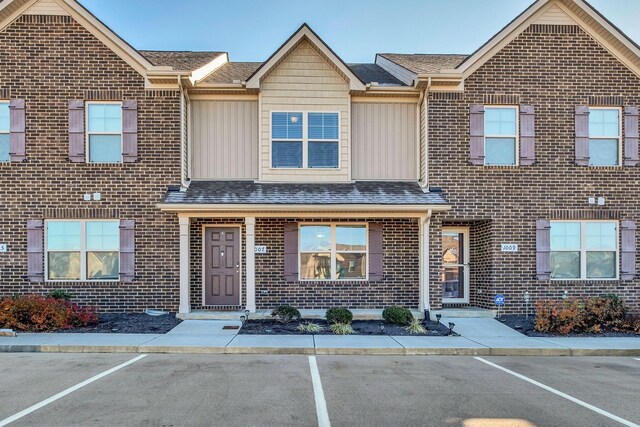 view of front of property featuring board and batten siding, brick siding, and uncovered parking