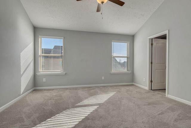 carpeted empty room with a ceiling fan, baseboards, and a textured ceiling