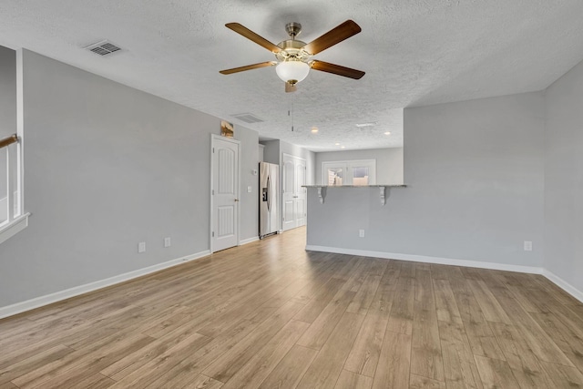 unfurnished living room with light wood-type flooring, a textured ceiling, ceiling fan, and visible vents