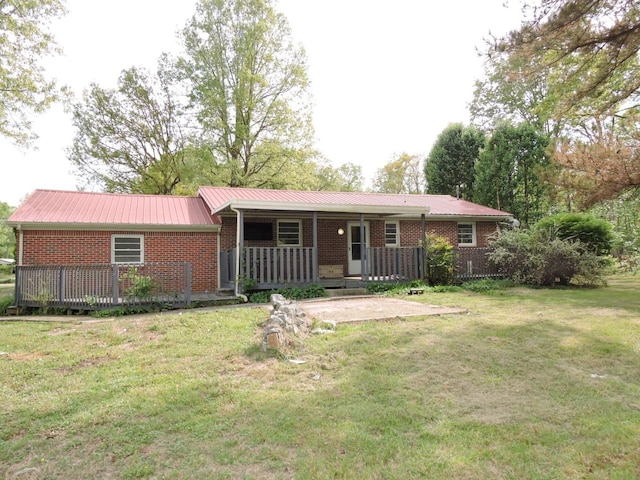 ranch-style home featuring a front lawn, brick siding, covered porch, and metal roof