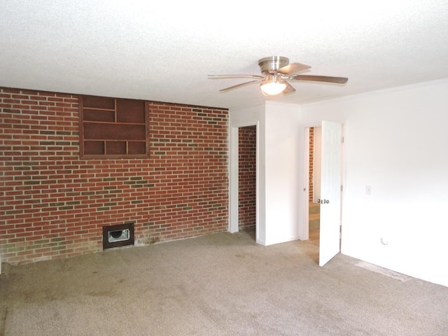 carpeted empty room with brick wall, a textured ceiling, and ceiling fan