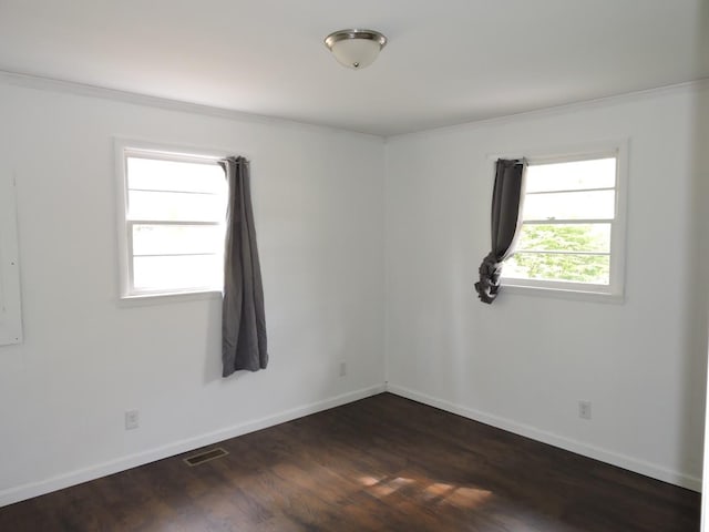 empty room with baseboards, visible vents, and dark wood-style flooring